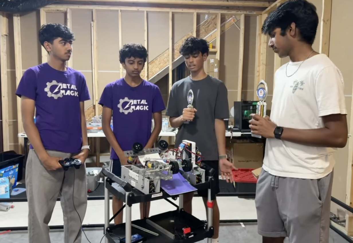 The Metal Magic FTC #23362 team standing with their competition robot and two trophies in their workshop